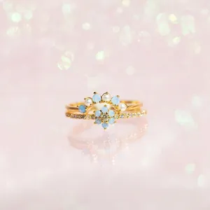 Elegant gold flower and crown ring set featuring blue opals and white pearls
