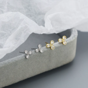 Macro shot of 925 sterling silver clover stud earrings in gold and silver finishes
