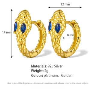 Macro detail of gold snake earrings featuring blue zircon eyes and diamond-cut scales
