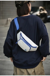 Nahaufnahme einer weißen Nylon-Brusttasche mit blauen Riemen und Reißverschluss am Model