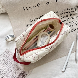 Primer plano del estuche acolchado con bordados rojos y espacio para papelería interna