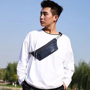 Detail of navy blue nylon crossbody bag with zipper pockets and adjustable gray strap