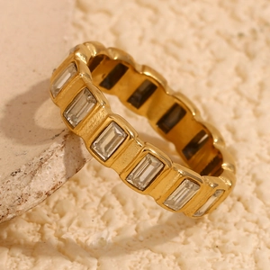 Macro shot of gold stainless steel ring with rectangular zircons and wavy texture edge