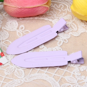 Close-up of purple matte metal hair clips with embossed text on beige lace fabric