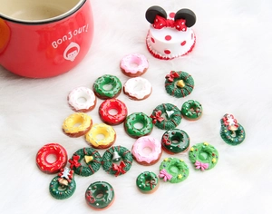 Flat lay of colorful resin Christmas wreath and donut charms on white plush background