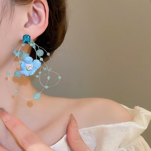 Detail of blue floral tassel earrings with long drop crystals on a fashion model