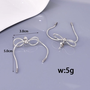 Silver bow stud earrings with long snake chain tassels on a clean purple background