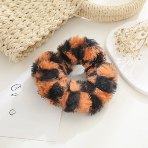 Detail of plush orange and black checkered scrunchie on cozy aesthetic background
