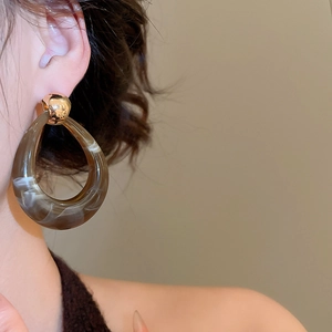 Detail of amber resin drop earrings with gold spherical studs on a female model
