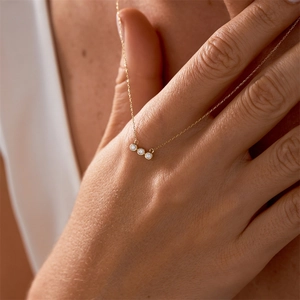 Gros plan d'un collier en or à trois pierres de naissance avec zircons ronds sur un mannequin