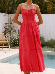 Detail of red spaghetti strap dress featuring ruched chest and tiered hemline by pool