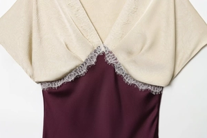 Detail of champagne and burgundy satin midi dress with white lace trim and V-neckline