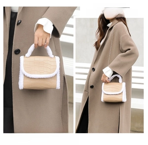 Macro detail of crocodile texture leather and white faux fur trim on elegant chain handbag