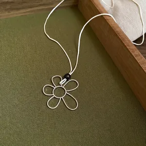 Minimalist flower pendant necklace with white cotton cord and pearl bead detail