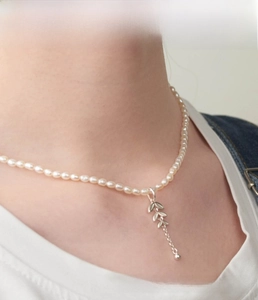 Close-up of a natural freshwater pearl necklace with a silver leaf pendant on a model