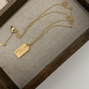 Gold Virgin Mary pendant necklace with colorful cubic zirconia on a wooden tray