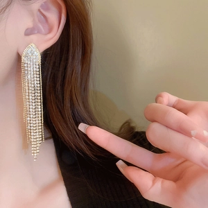 Detail of long gold tassel earrings with shimmering rhinestones on a model
