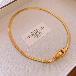 Gros plan sur le collier chaîne serpent dorée avec un fermoir magnétique style boucle de ceinture
