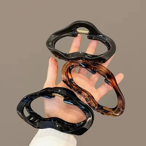 Set of three wave-shaped jelly hair claws in black and amber with gold spring detail