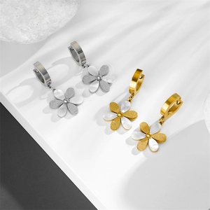 Titanium steel flower earrings with gold finish and white shell petals on white surface