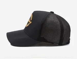 Close-up of black trucker hat showing breathable mesh and gold embroidered logo