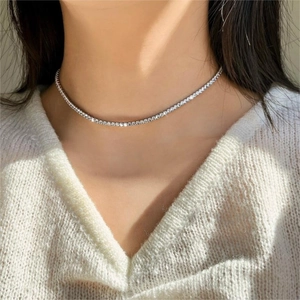 Close-up of a silver tennis choker necklace with sparkling zircons worn by a model
