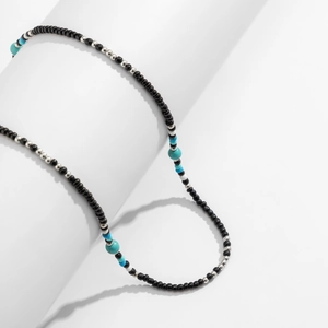 Detail shot of bohemian beaded necklace with turquoise accents on a white display pedestal