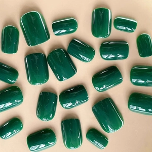 Glossy emerald green press-on nails set in various sizes on a beige background