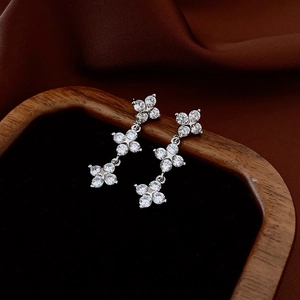 Detailed view of silver flower earrings featuring three stacked petals with sparkling crystals