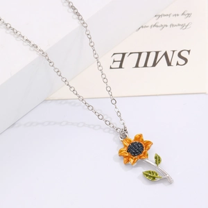 Détail du pendentif tournesol avec pétales jaunes et perle sur une chaîne en argent