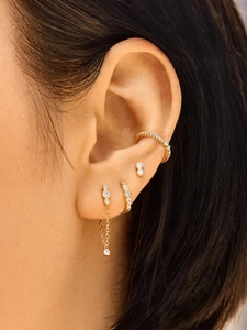 Detailed close-up of 18K gold earrings set with pearls and zircon on a model ear