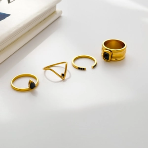 Macro detail of four gold rings set featuring black zircon and geometric water-drop designs
