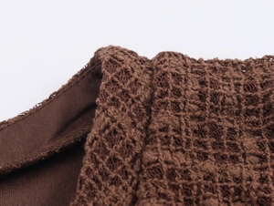 Macro detail of dark brown knit fabric with intricate hollowed-out crochet texture