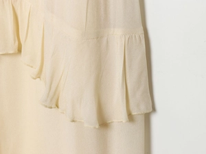 Detail of light yellow tiered dress showing delicate ruffled edges and crinkled fabric texture
