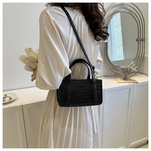 Chic black crocodile pattern handbag styled with an elegant cream pleated dress