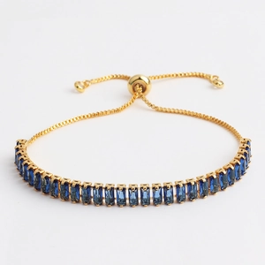 Detail of adjustable gold slider bracelet with rectangle deep blue zircon stones