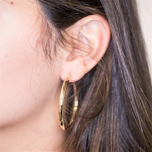 Detailed view of polished thick gold hoop earrings on a model for a minimalist style
