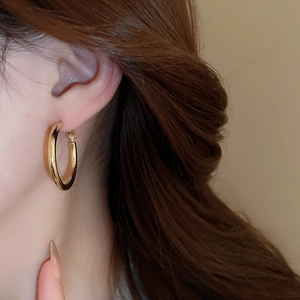 Close-up of polished gold hoop earring on model showing sleek metallic finish