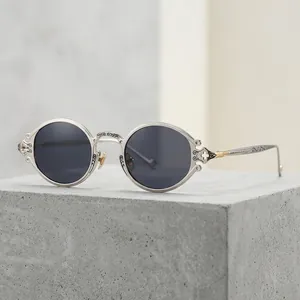 Steampunk oval sunglasses with silver carved hollow frames on a natural stone surface