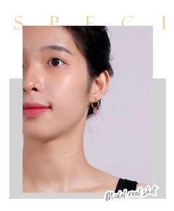 Model wearing gold heart-shaped earrings set with purple zircon stones in a real shot