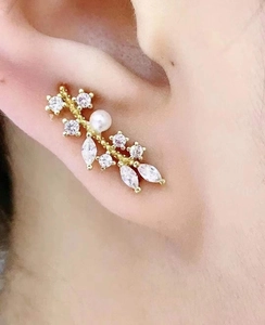 Detail view of gold branch ear cuff with sparkling marquise zircons and white pearl inlay