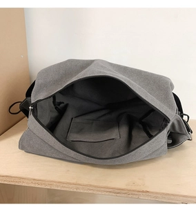 Detail view of large grey canvas messenger bag showing interior pocket and zip closure