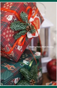 Detail of Christmas gift wrapping paper with Santa patterns, pine cones and festive ribbons