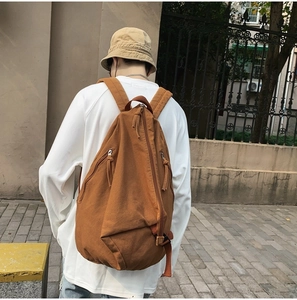 Brown washed canvas crossbody backpack with unique diagonal zipper and single shoulder strap