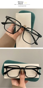Detail view of bright black eyeglasses frame with green velvet case and brand cards