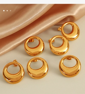 Macro shot of gold hollow irregular disc earrings on champagne silk and stone surface