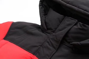 Détails du col et de l'épaule d'une doudoune à capuche bicolore rouge et noire