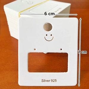 Detailed view of white jewelry display card with gold smiley icon and 925 silver text