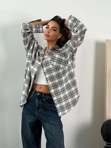 Women's grey and white plaid shirt worn over a white crop top with blue jeans