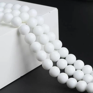 Strands of white matte sunstone round beads for DIY jewelry making on a modern display